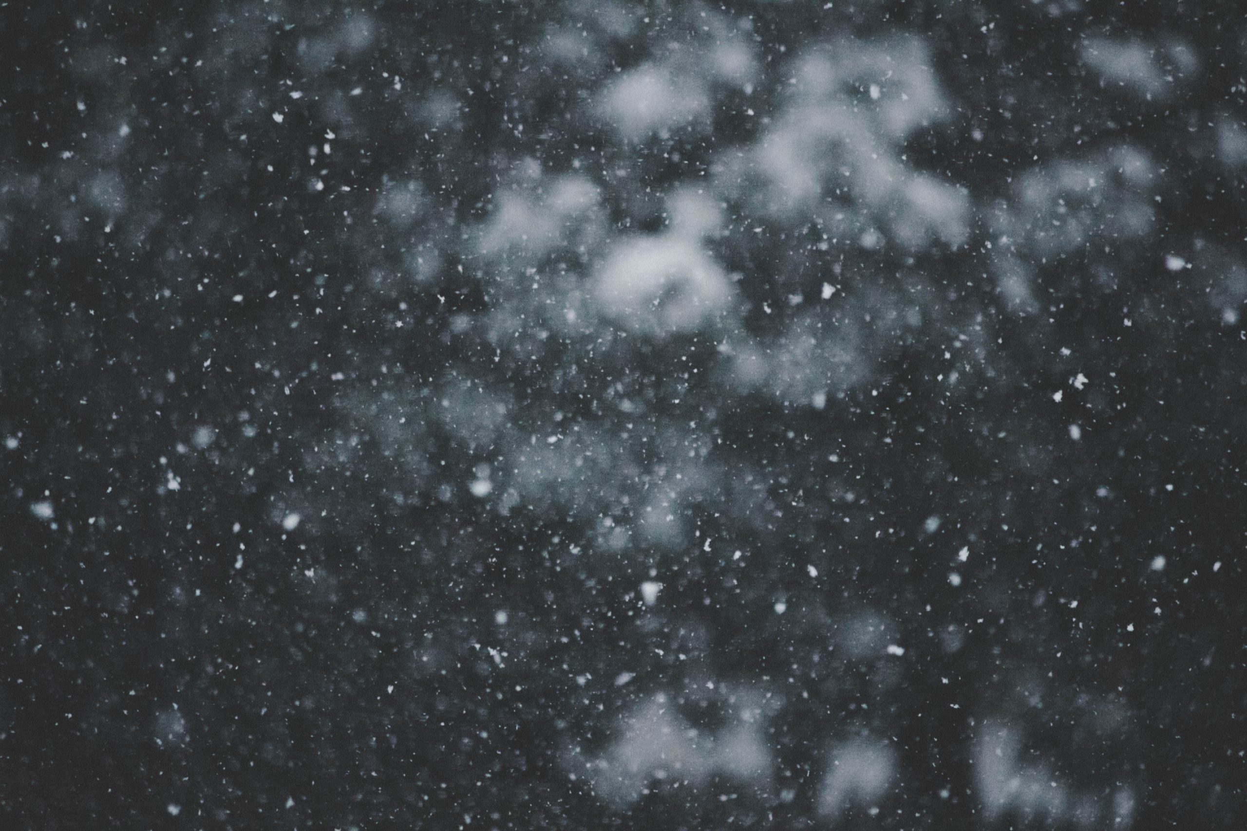 Snowflakes falling against a dark sky, resembling visual snow