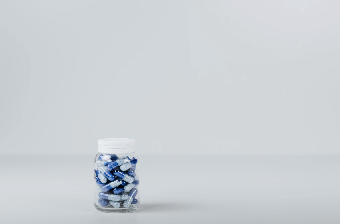Jar of blue and white capsules on a grey surface